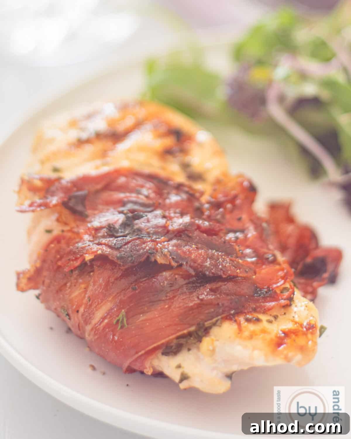 A white plate with chicken fillet with Serrano ham and Italian herbs from the BBQ