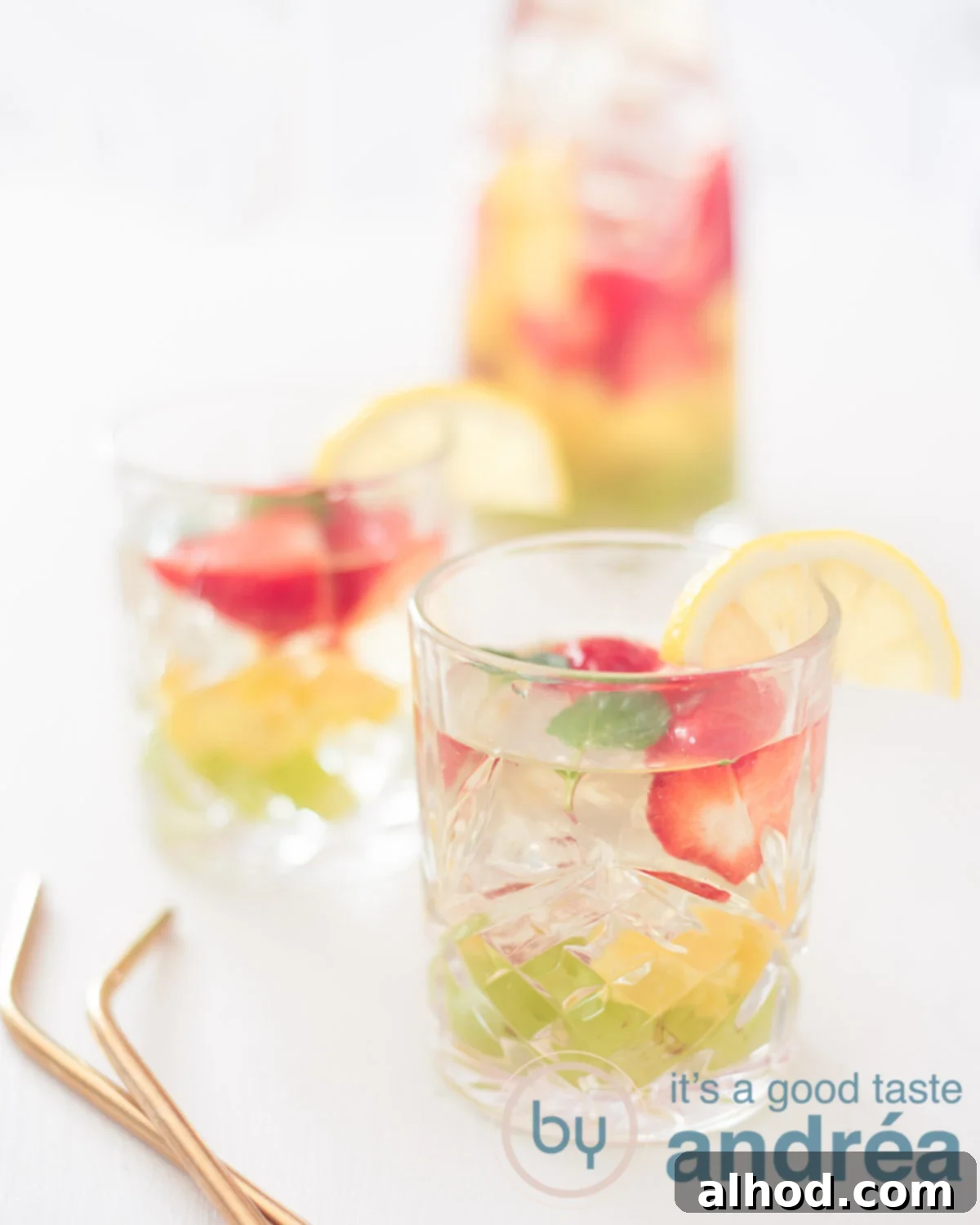 Vibrant Clerico Cocktail 5 clerico the white sangria, two glasses on a white background with grapes, mango and strawberries. In the back a jar filled with clerico