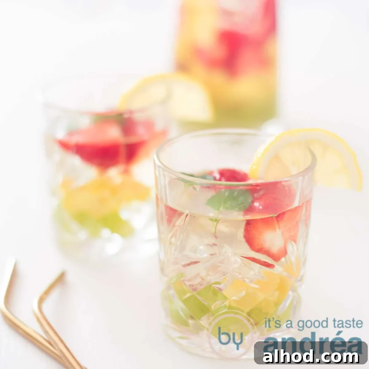 Crafting the Perfect Clerico Punch 6 A square photo with two glasses filled with white sangria with fruit on a white background. On the left part of two golden straws.