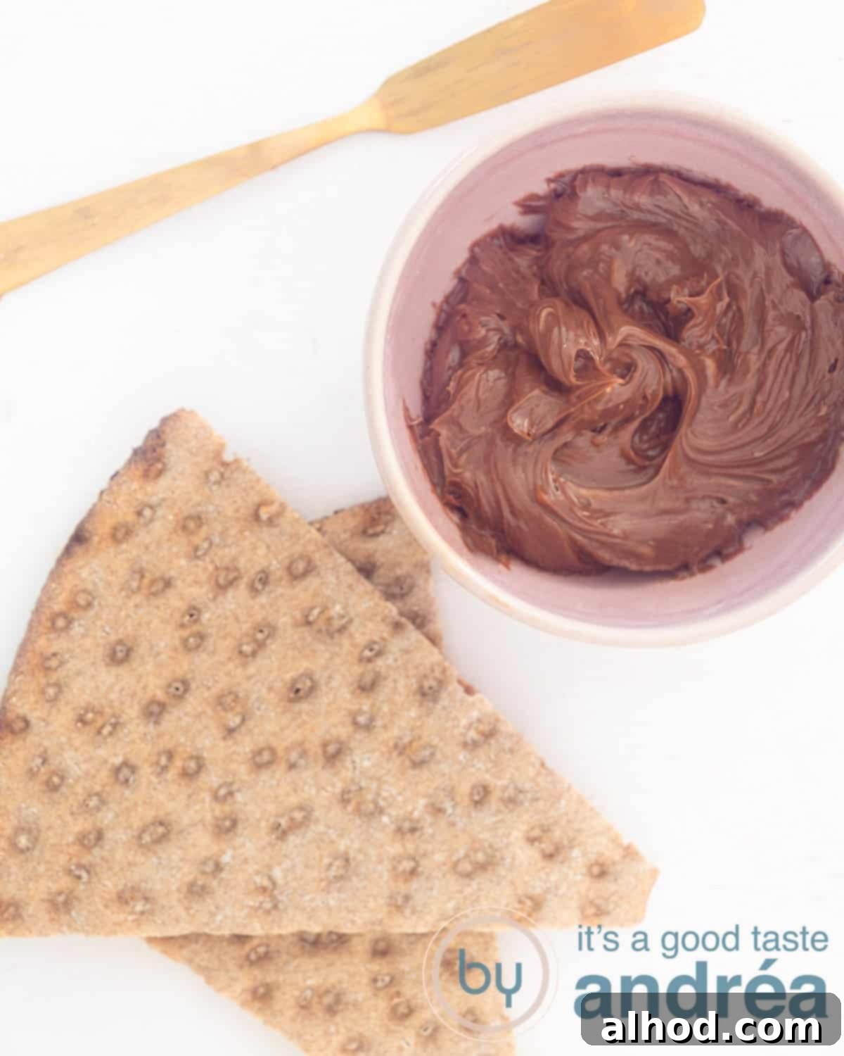 A bowl of homemade chocolate butter spread with crackers and a knife, ready to be enjoyed.