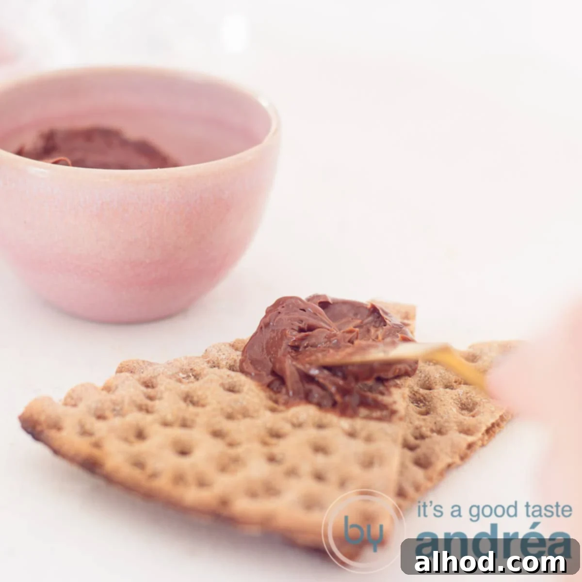 Decadent Chocolate Butter Spread 6 A person is spreading chocolate butter on a cracker, highlighting its smooth and spreadable texture.