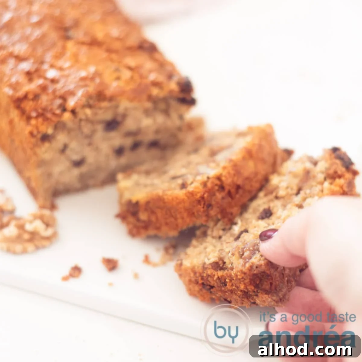 Wholesome Granola Cake 6 A square photo showing part of a granola cake, two slices cut off. A hand grabs the front slice