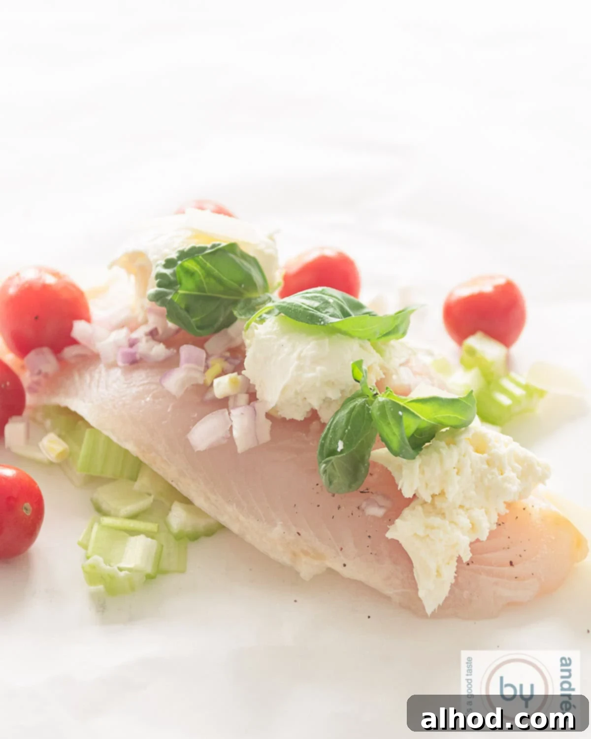 Cod en Papillote 3 A baking paper with unbaked vegetables, cod fillet, mozzarella and basil on it