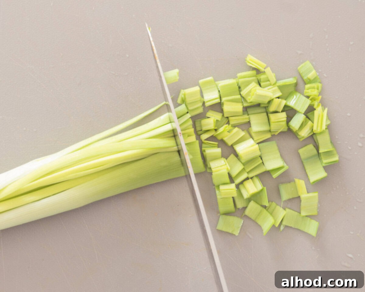 Speedy Leek Cleaning Made Simple 6 Hands holding a quartered leek under cold running water, spreading the layers apart to rinse away hidden sand and dirt, with the root still intact.