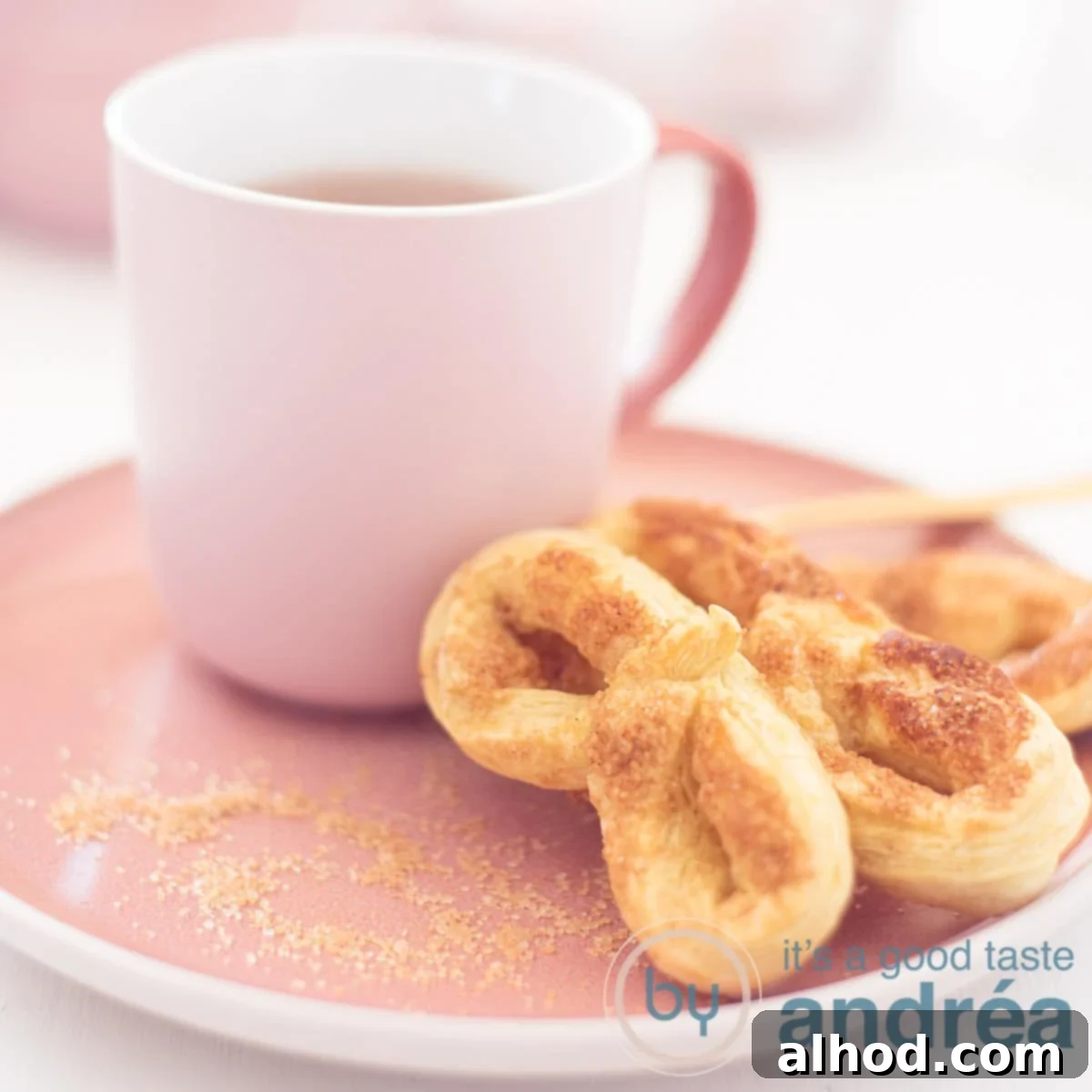 Krakelingen Sweet Dutch Pretzel Delights 6 A square photo with a pink plate with three pretzels and a pink cup filled with tea.