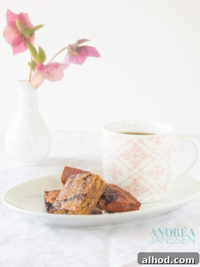 Luscious Honey Blondies 2 A plate with honey blondies and a pink white cup. In the background a white vase with flowers, creating a cozy and inviting scene.