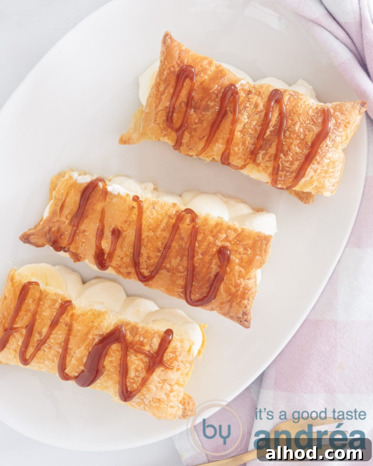 Caramelized Banana Mille-Feuille 2 A top-down photo of three puff pastry napoleons with caramel sauce on a white background, garnished with fresh banana slices.