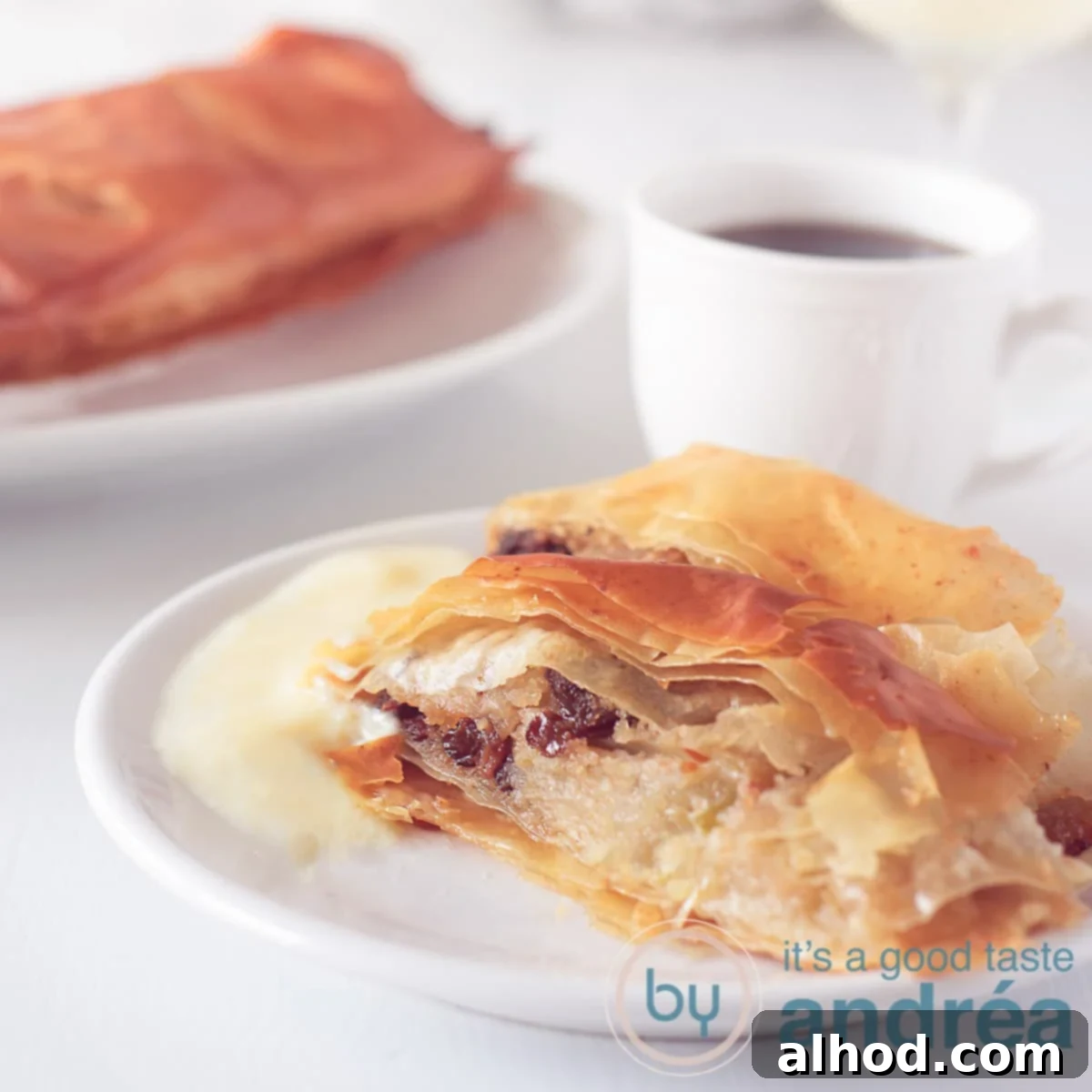 Authentic German Apple Strudel 7 A square photo with a tempting slice of German Apple Strudel, a cozy cup of coffee, and more strudel in the background, inviting you to indulge.