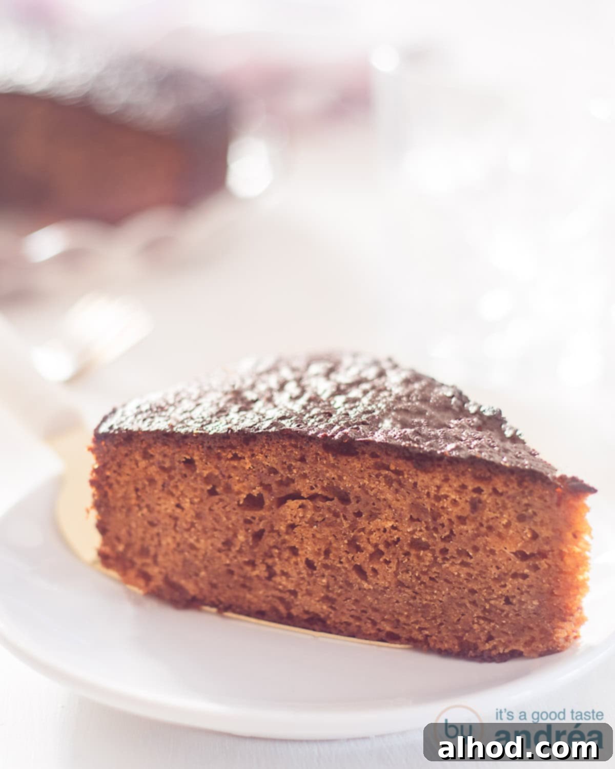 Melt In Your Mouth Sticky Toffee Cake 2 A piece of Sticky toffee cake on a white plate. Some extra cake in the background