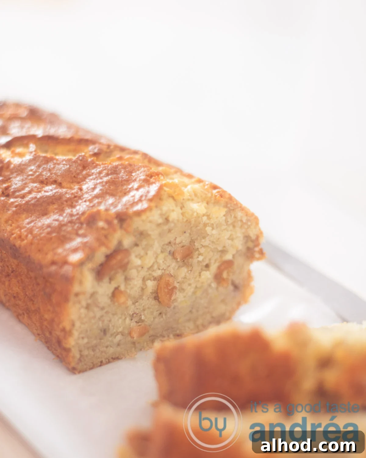 Golden Cashew Banana Loaf 3 banana bread with cashew nuts on a wooden board. Two pieces sliced off.
