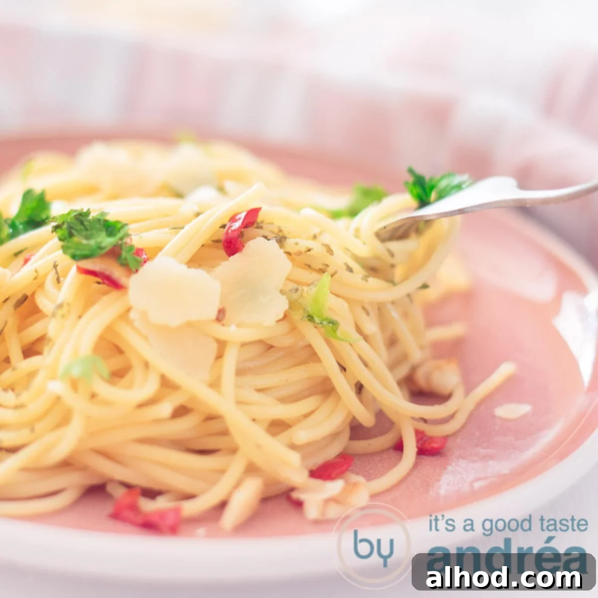 Rustic Chili Garlic Pasta 6 A square photo showing part of a pink plate, a mountain of spaghetti seasoned with pepper, olive oil and garlic, parsley and sheared parmesan cheese