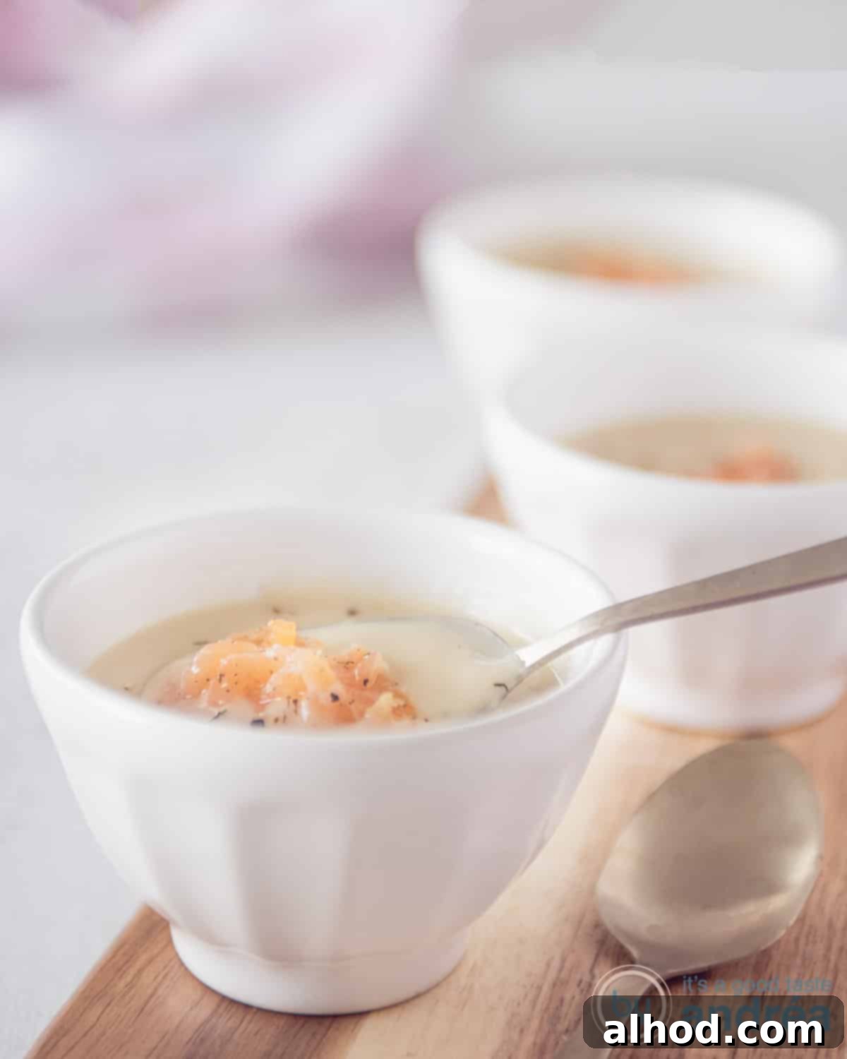 Regal Dutch Broth 2 An overhead photo with three white cups on a wooden board filled with creamy chicken soup with smoked salmon and dill, ready to be served.