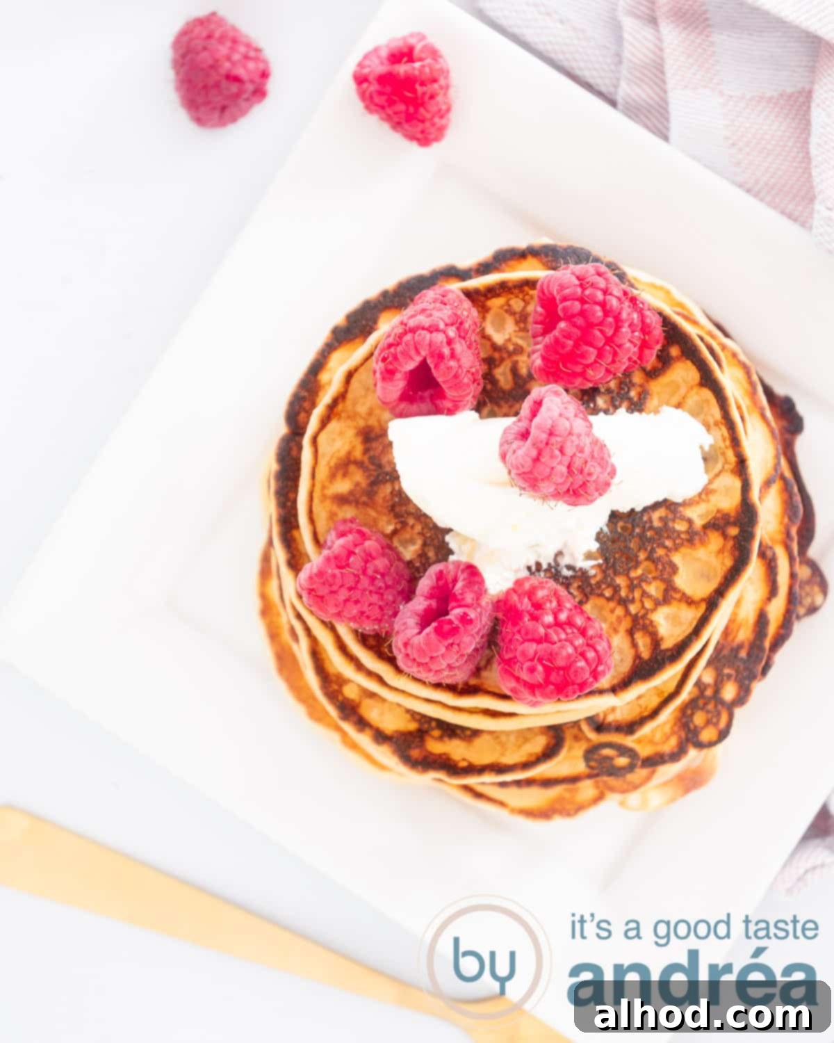 Sweet and Tangy Raspberry Creme Fraiche Pancakes 2 A photo from above of a stack of pancakes, raspberries and crème frache on a white plate. Top left some raspberries, bottom right part of a golden fork.