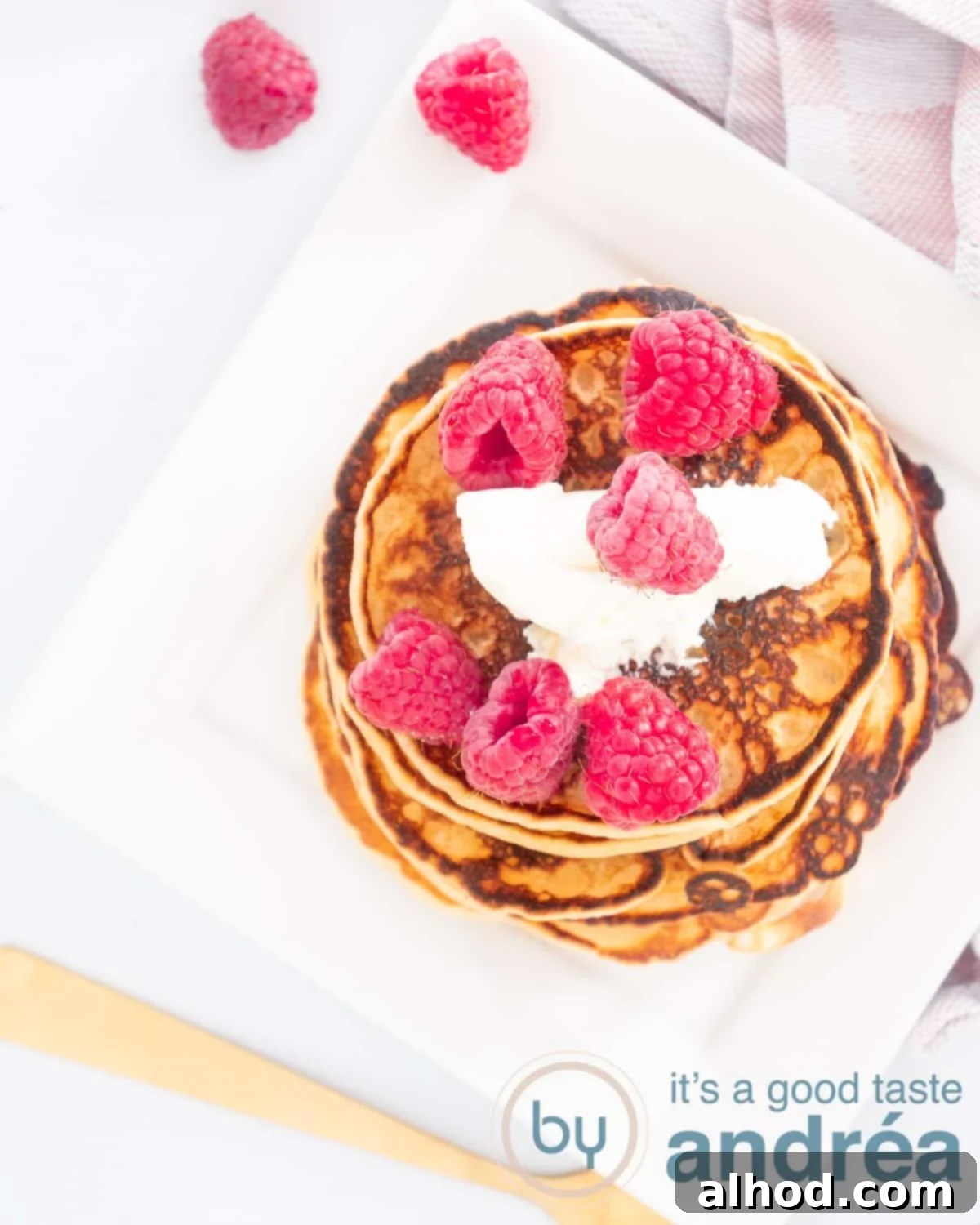 Decadent Raspberry Crème Fraîche Pancakes 2 A top-down view of a stack of golden-brown fluffy pancakes, beautifully garnished with a swirl of creamy crème fraîche and an abundance of bright red, fresh raspberries. A golden fork gently rests on the side, ready to dig in. The plate is white, suggesting a clean and elegant presentation. This image perfectly captures the deliciousness and airy texture of the pancakes, promising a delightful culinary experience.