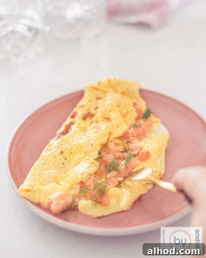 Gourmet Smoked Salmon Omelette 3 A height photo with a pink plate with an omelette filled with smoked salmon. A golden fork pierces it.