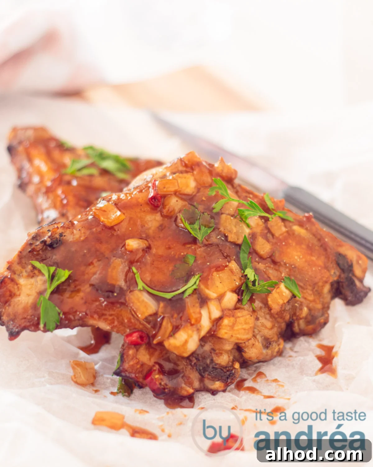 Fall-Off-The-Bone Slow Cooker BBQ Spareribs 5 Two pieces of ribs on top of each other covered with BBQ sauce and parsley