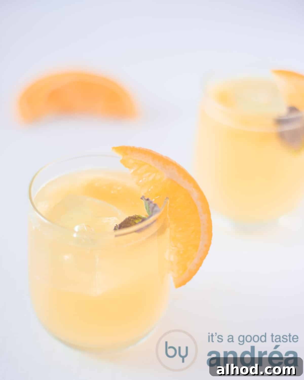 Sunrise Elderflower Sparkler 2 A white background with two glasses, diagonal placed. They're filled with elderflower and orange cocktail