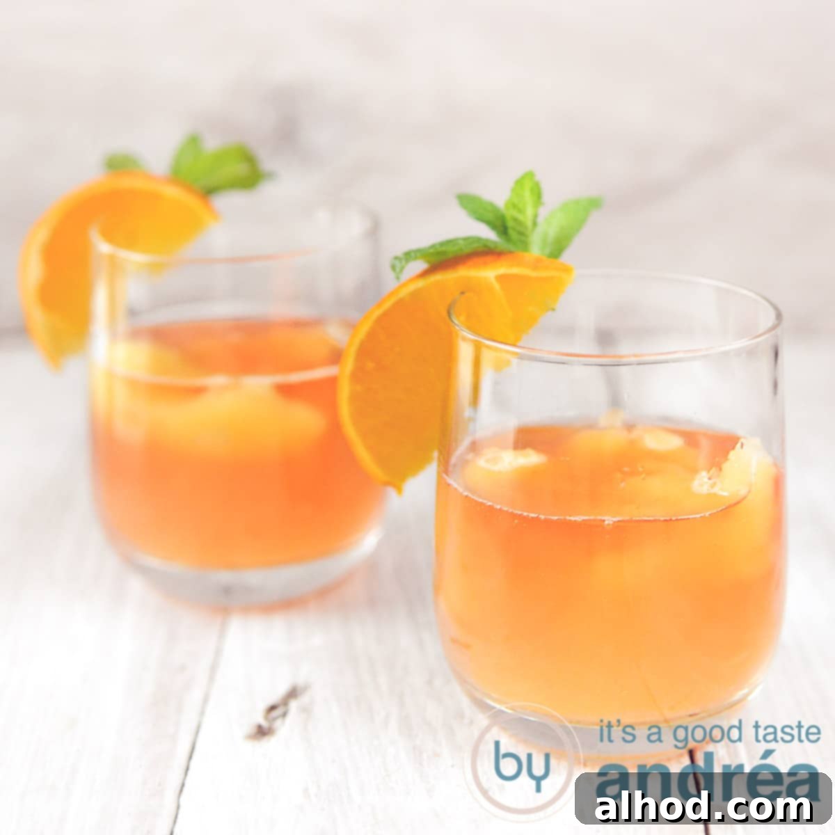 Sunrise Elderflower Sparkler 6 A square photo with two glasses with orange elderflower cocktail on a wooden floor.