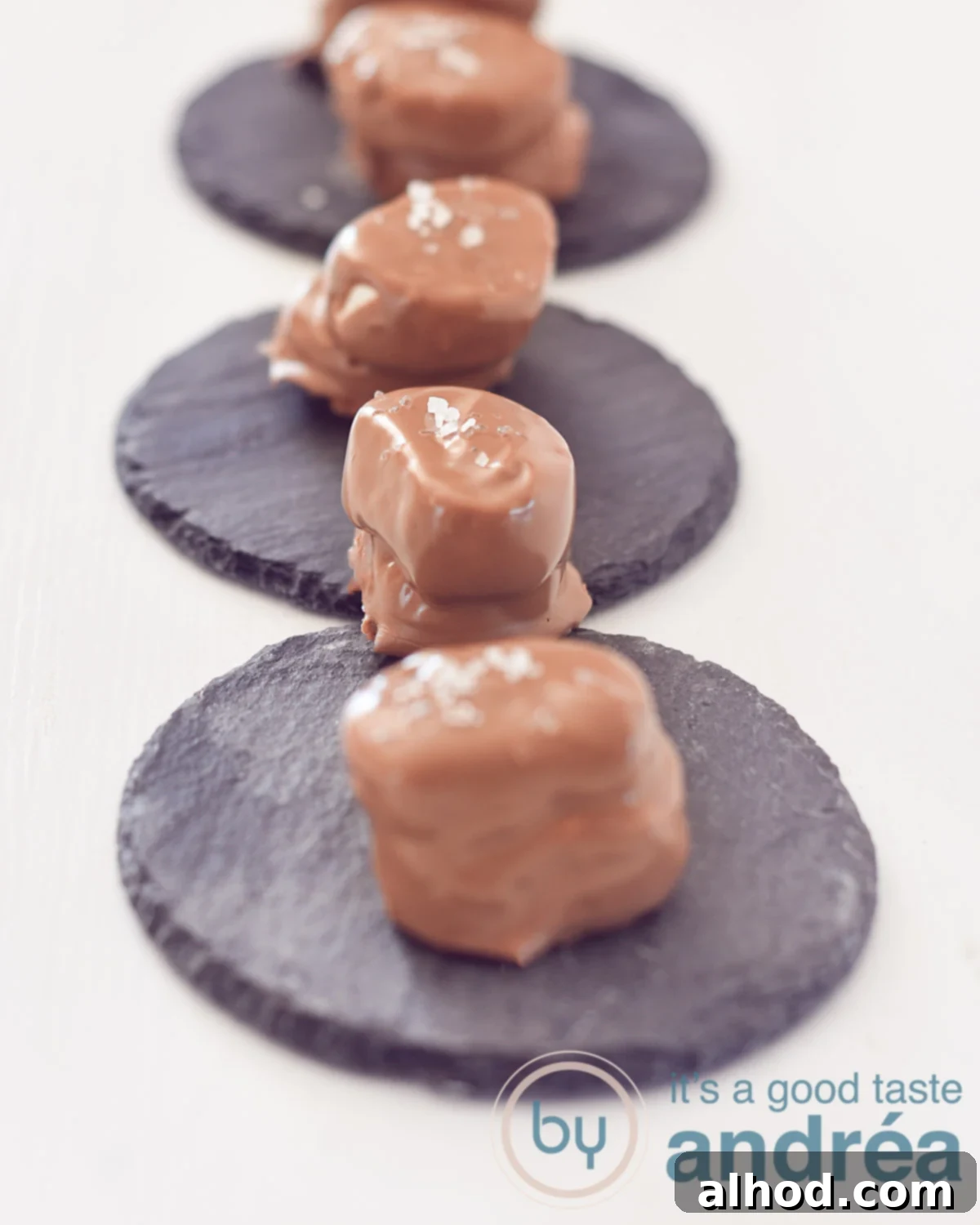 Boozy Chocolate Marshmallows with a Salty Kiss 2 Beer bonbons on a stone plate on a white background four chocolates in a row.