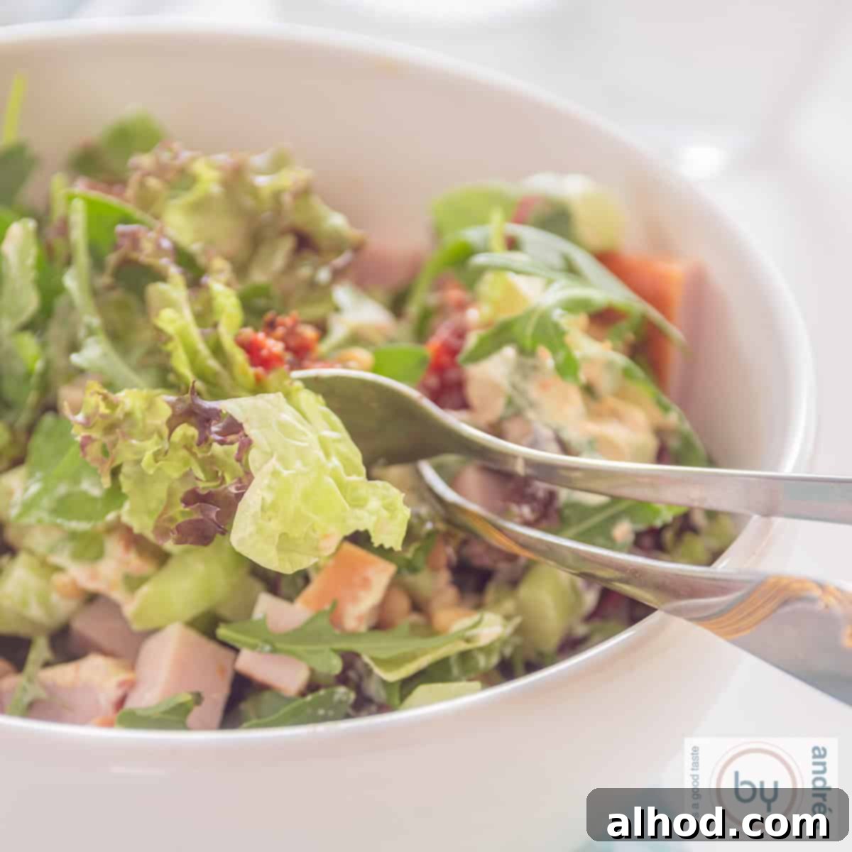Flavorful Smoked Chicken Salad Made in 10 Minutes 4 A square photo of a white bowl with green salad, smoked chicken and sun-dried tomatoes.