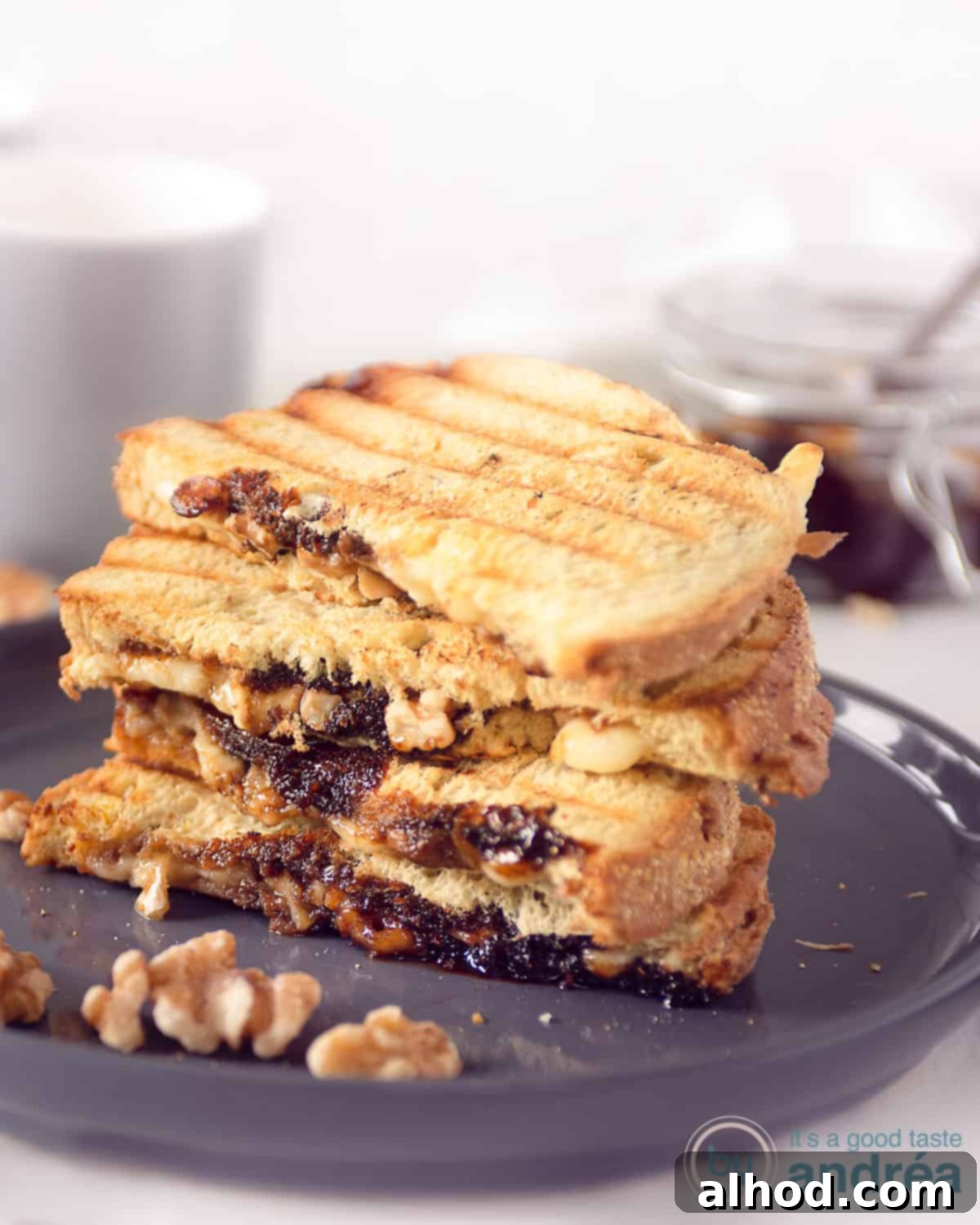 Warm Camembert Melt 3 A grey plate with a staple Camembert grilled sandwiches. Some walnuts in front.