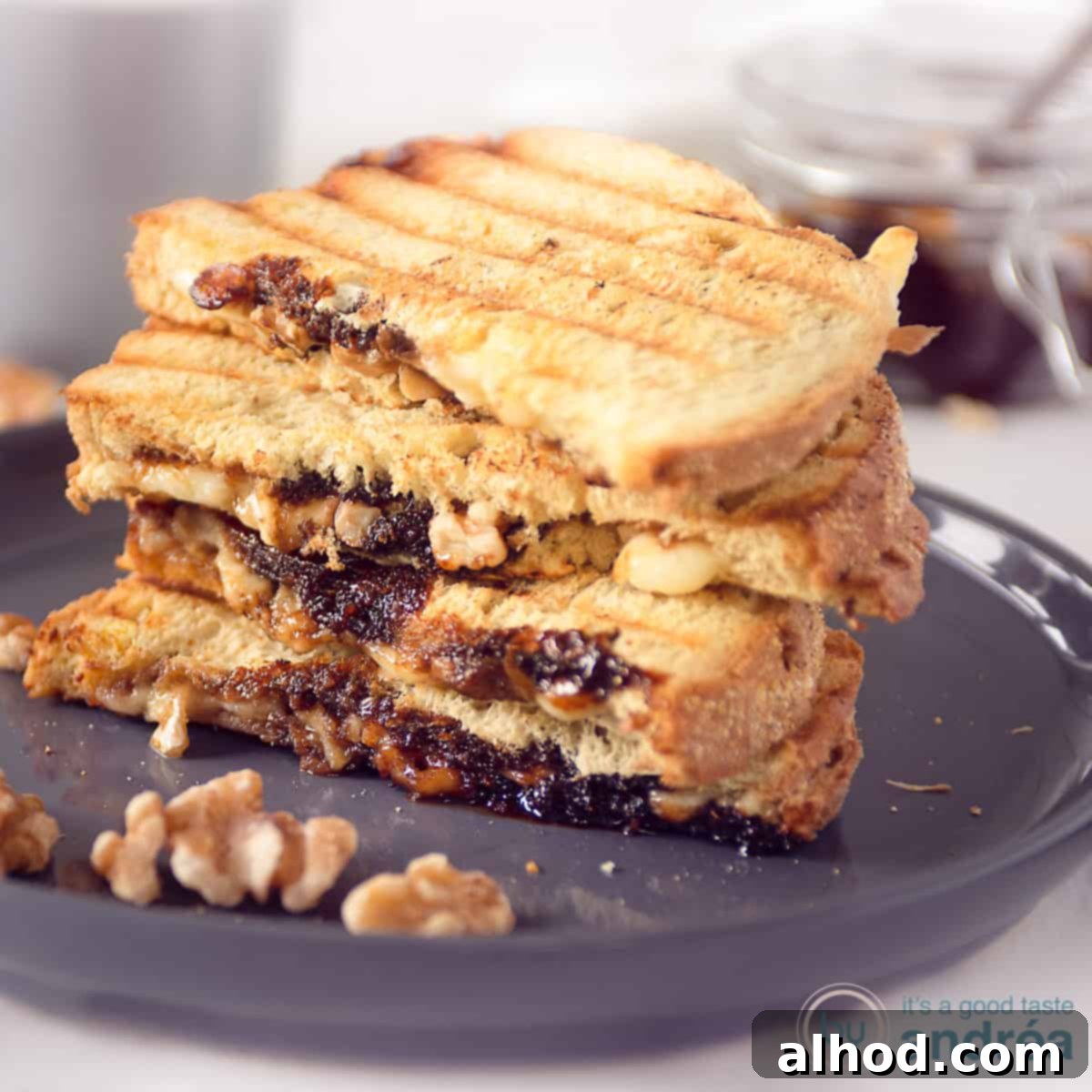 Warm Camembert Melt 4 A square photo with a gray plate with a stack of toasted sandwiches with Camembert and walnuts in front.