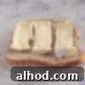 A slice of bread topped with perfectly arranged thick slices of Camembert cheese, ready for the next step of sandwich assembly.