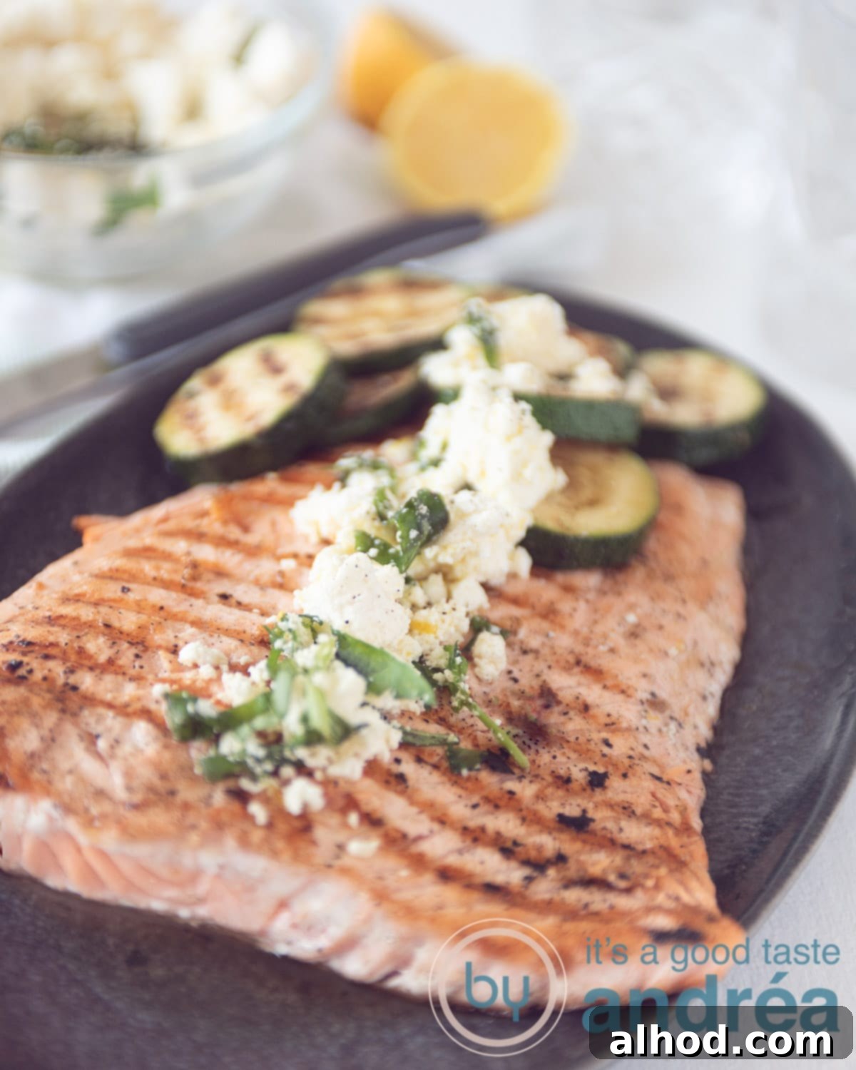 Grilled Salmon with Zucchini Delight 5 A large grilled salmon, with grilled zucchini and a feta dressing on top, served on a plate.