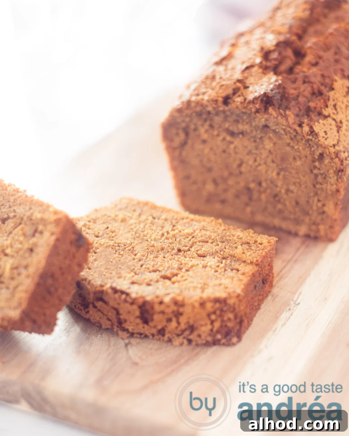 Dutch Gingerbread Loaf 2 Half of a moist Dutch Ontbijtkoek (gingerbread spice bread) on a white cloth, with a plate of butter and a glass of milk on the right, inviting a delicious snack.