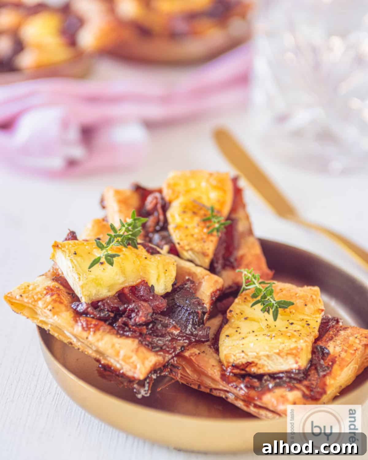 Golden Brie and Caramelized Onion Puffs 3 A bowl with three puff pastry snacks with brie, bacon and caramelized onions.