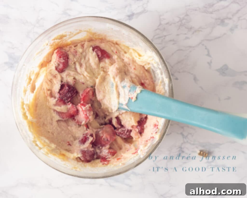 Dreamy Strawberry Ricotta Cake 6 Gently mixing fresh strawberries into the cake batter.