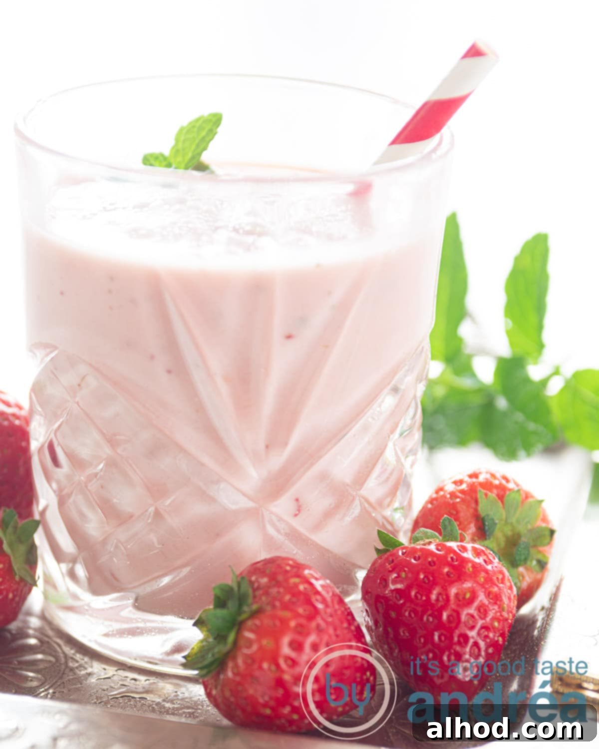 Zesty Berry Orange Blend 2 A glass of creamy strawberry orange smoothie with fresh strawberries and mint on the side, ready to be enjoyed.