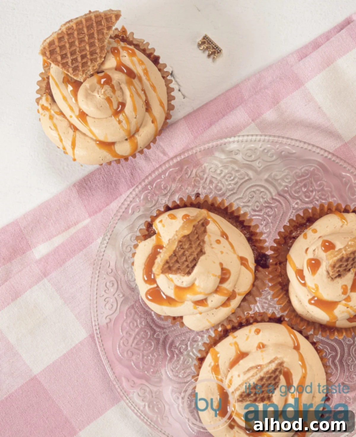 Four beautifully decorated stroopwafel cupcakes with caramel frosting, viewed from the top, garnished with a piece of stroopwafel.