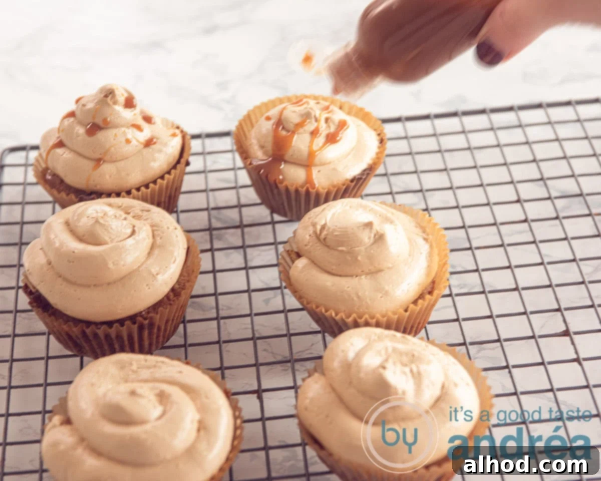 Easy Dutch Stroopwafel Cupcakes 7 A freshly frosted stroopwafel cupcake being drizzled with rich caramel sauce, ready for a final garnish.