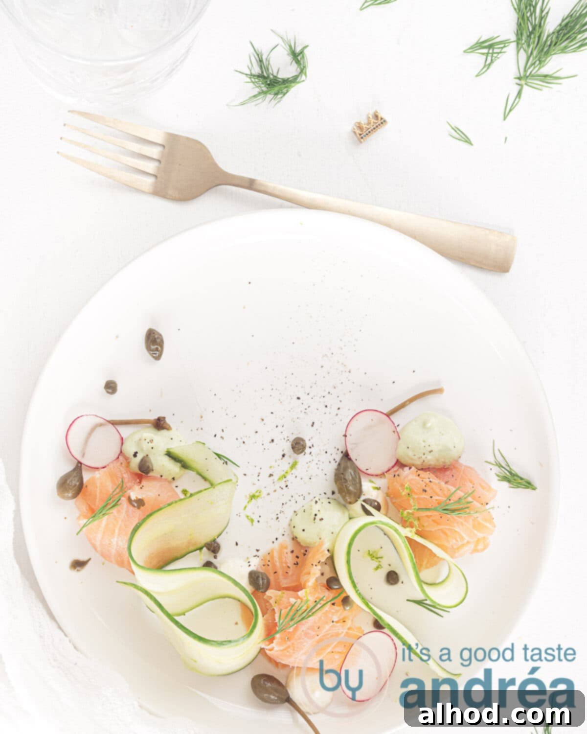 Effortless Smoked Salmon Cucumber Salad 2 A beautifully plated deconstructed smoked salmon salad with cucumber ribbons, avocado and horseradish cream, garnished with dill. A fork rests beside it.