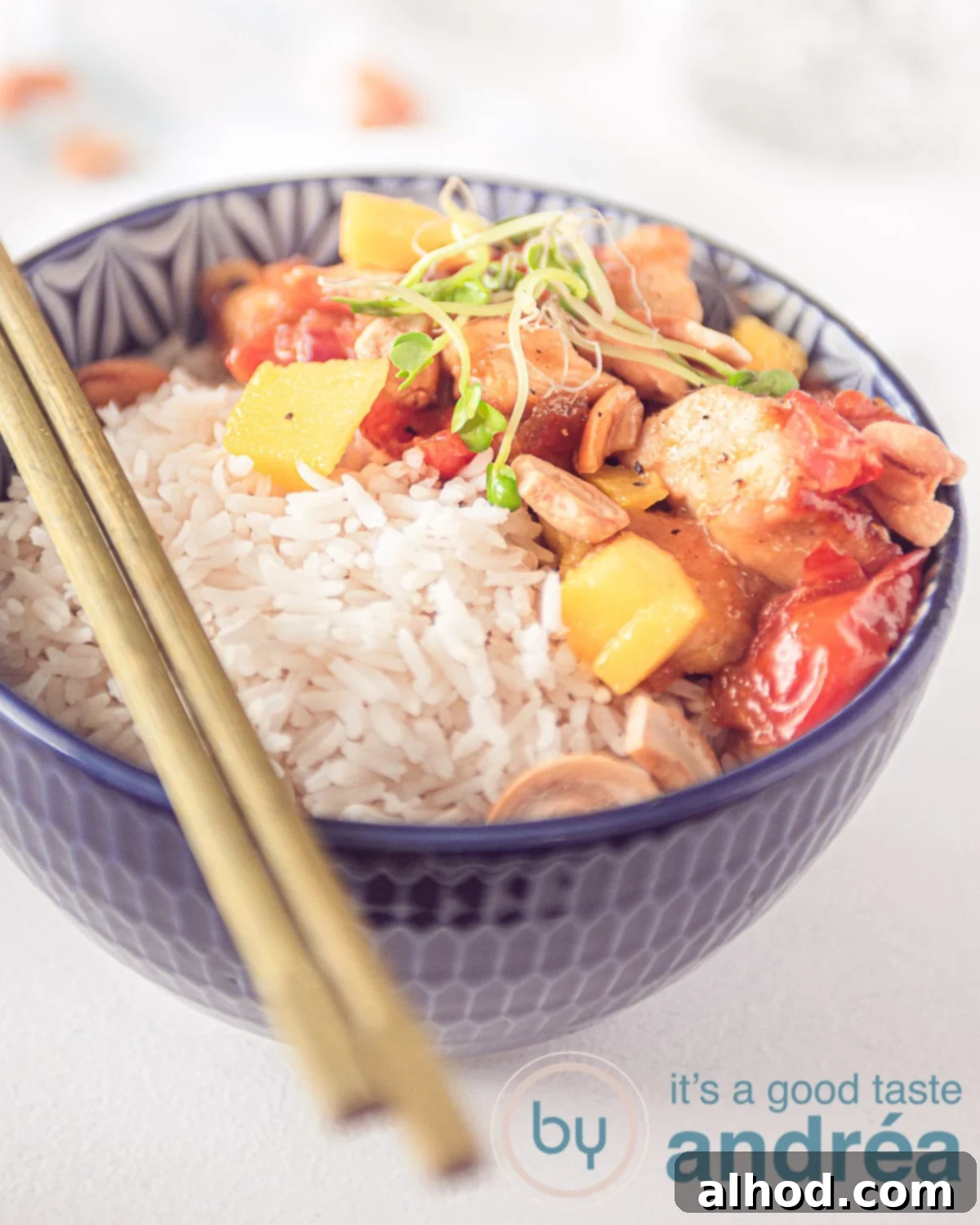 20-Minute Sticky Honey Soy Mango Chicken 2 A vibrant bowl of Honey Soy Chicken with rice, fresh mango, cherry tomatoes, and cashews, ready to be enjoyed with chopsticks.
