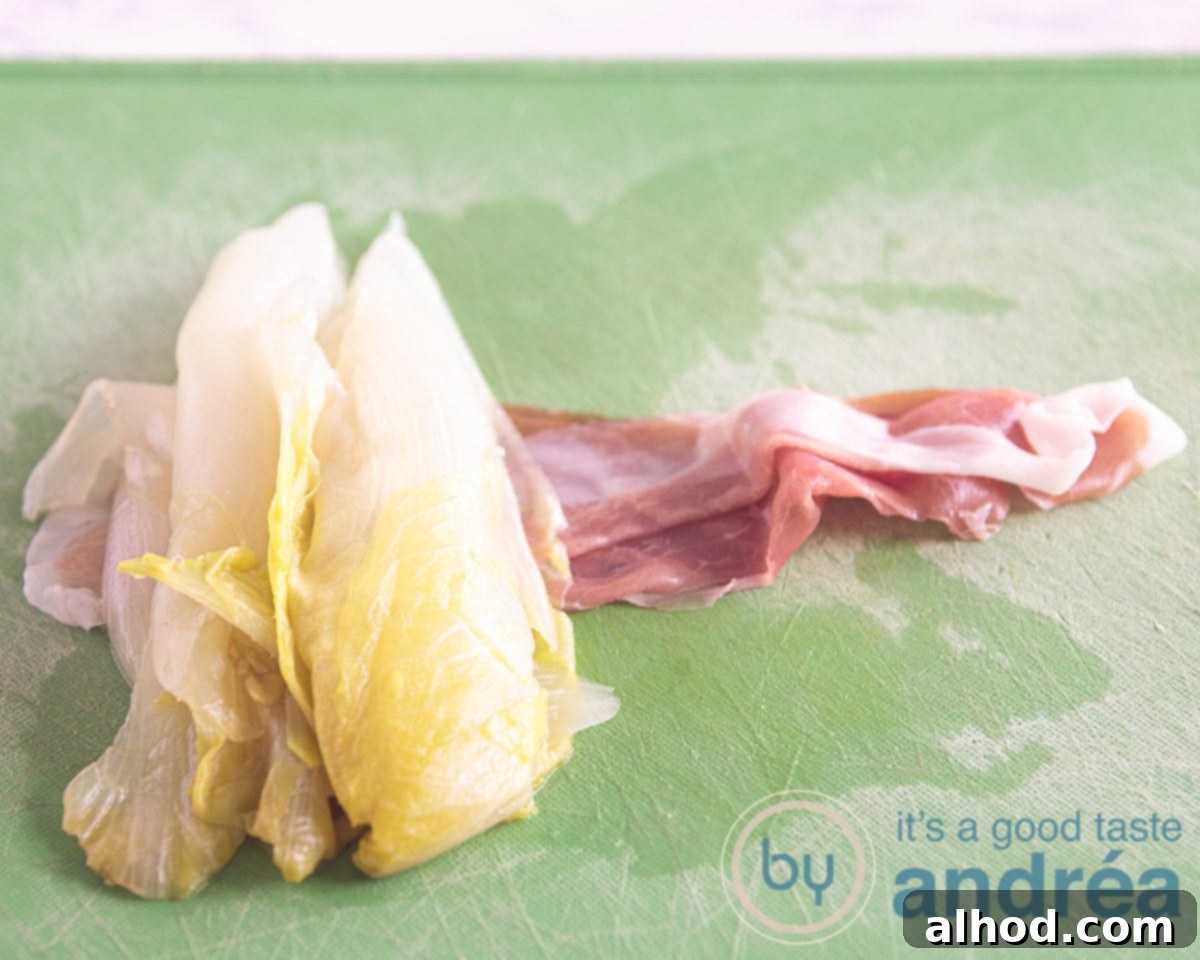 Belgian Endive Bake with Ham and Chevre 6 A chicory half being carefully placed on a slice of Prosciutto ham, illustrating the process of wrapping the endive for the casserole.