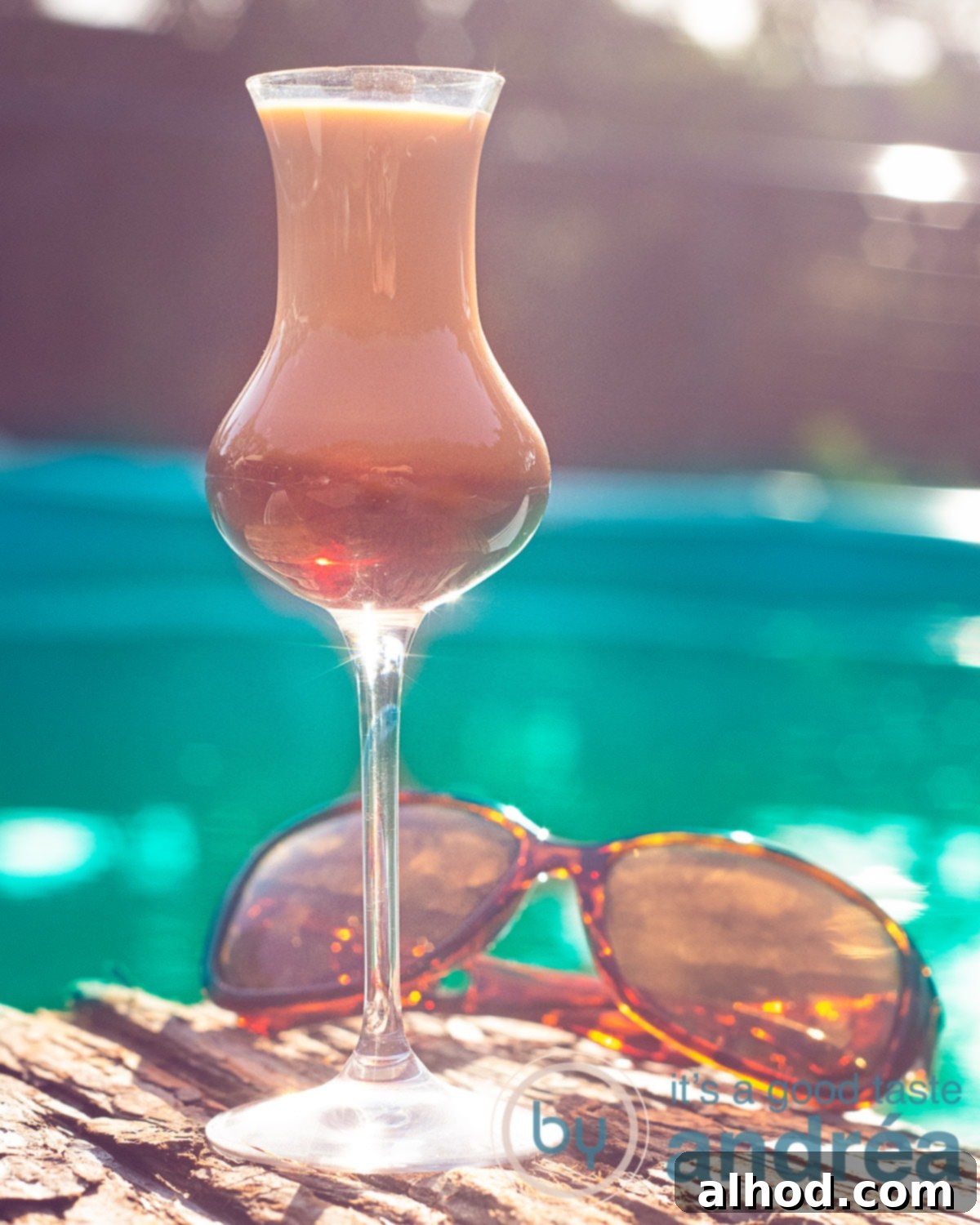 Creamy Amarula Indulgence 2 A beautifully layered Amarula Coffee Cocktail, showcasing a rich coffee base and creamy Amarula topping, garnished with a cinnamon stick, set against a serene pool background.
