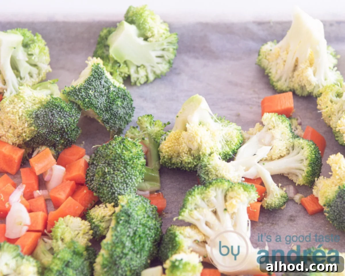 Delicious Ham and Carrot Rice Bake 4 Diced carrots, small broccoli florets, and thinly sliced onions spread evenly on a parchment-lined baking sheet, glistening with olive oil, ready for roasting