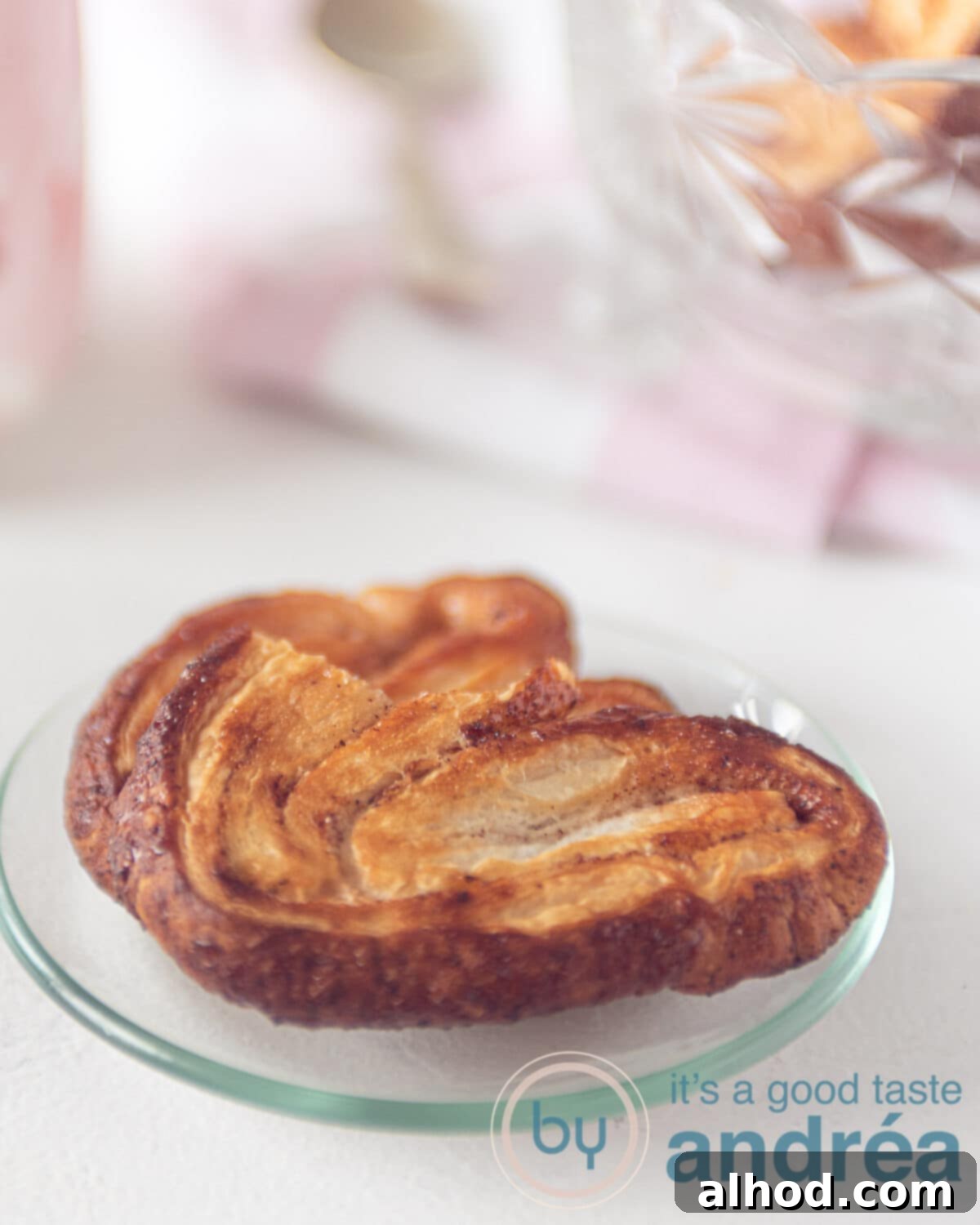 Simple 3-Ingredient Cinnamon Palmiers 2 two elephant ear cookies on a plate. One has taken a bite out of it.