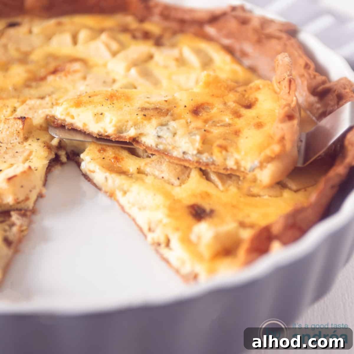 A gourmet Gorgonzola Apple Quiche with a slice removed, revealing the creamy filling, caramelized onions, and tender apple pieces.