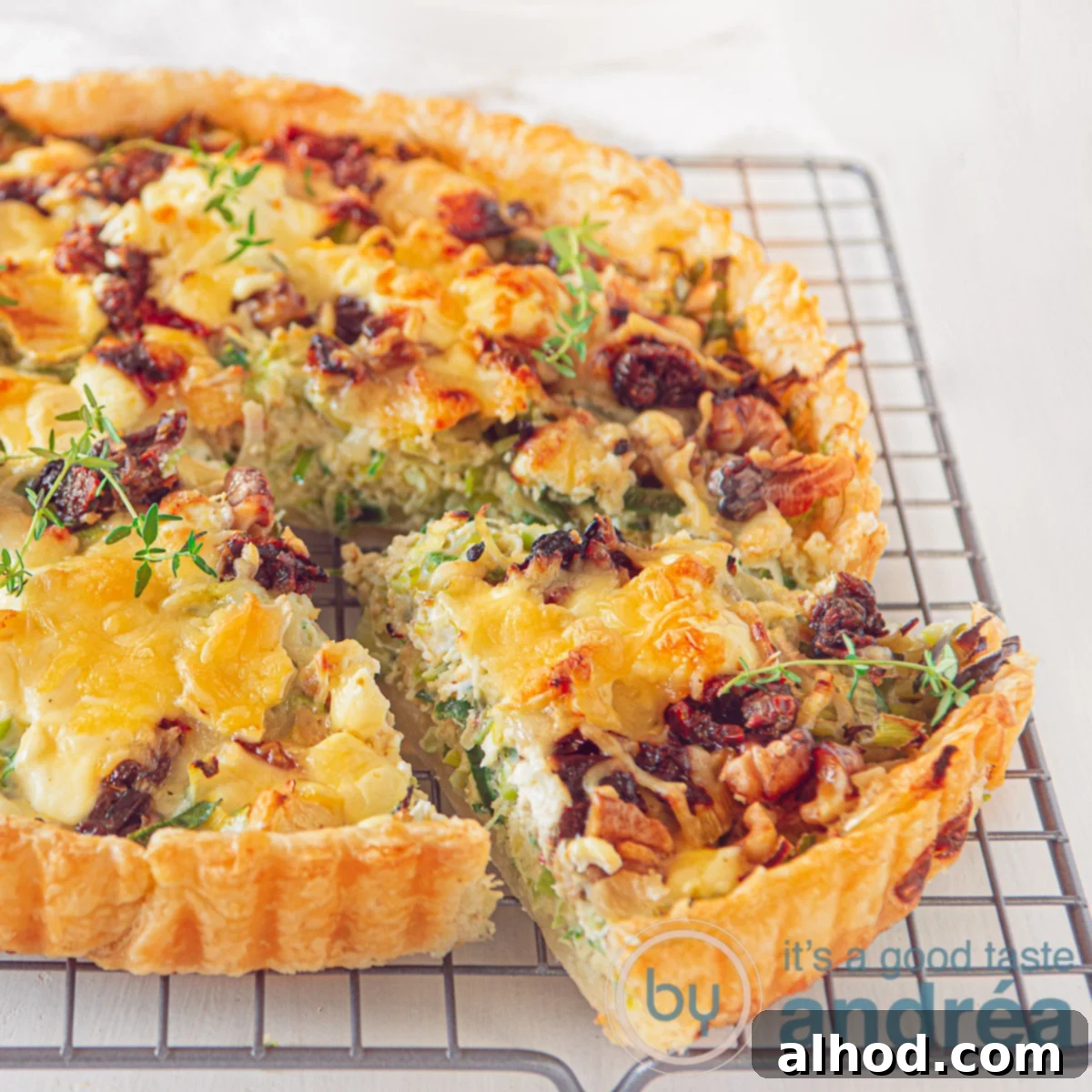 A square photo of a quiche with leeks, goat cheese and honey on a rack. A white background