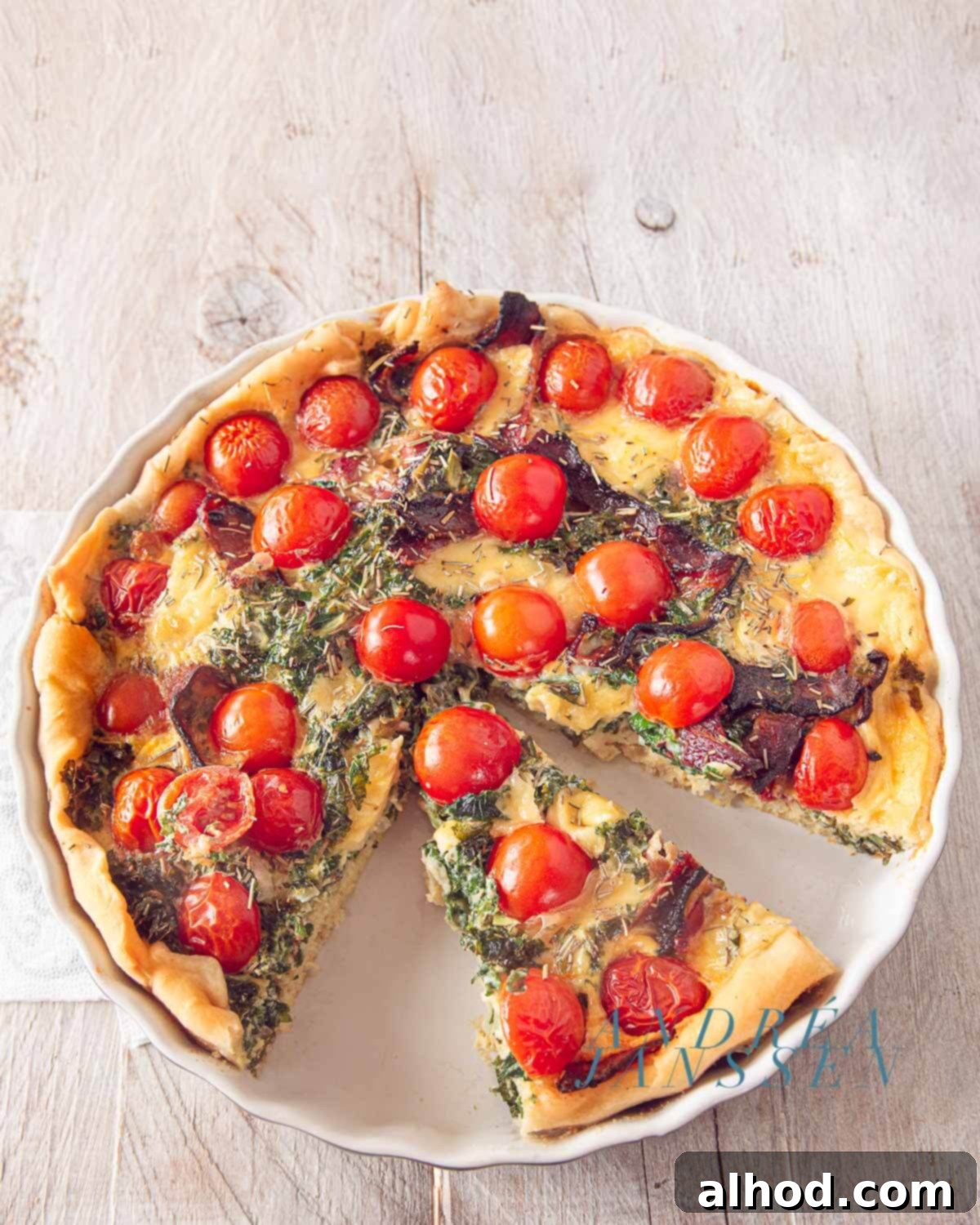 A close-up of a hearty Kale, Tomato, and Bacon Quiche, showing the vibrant ingredients baked into a golden crust.