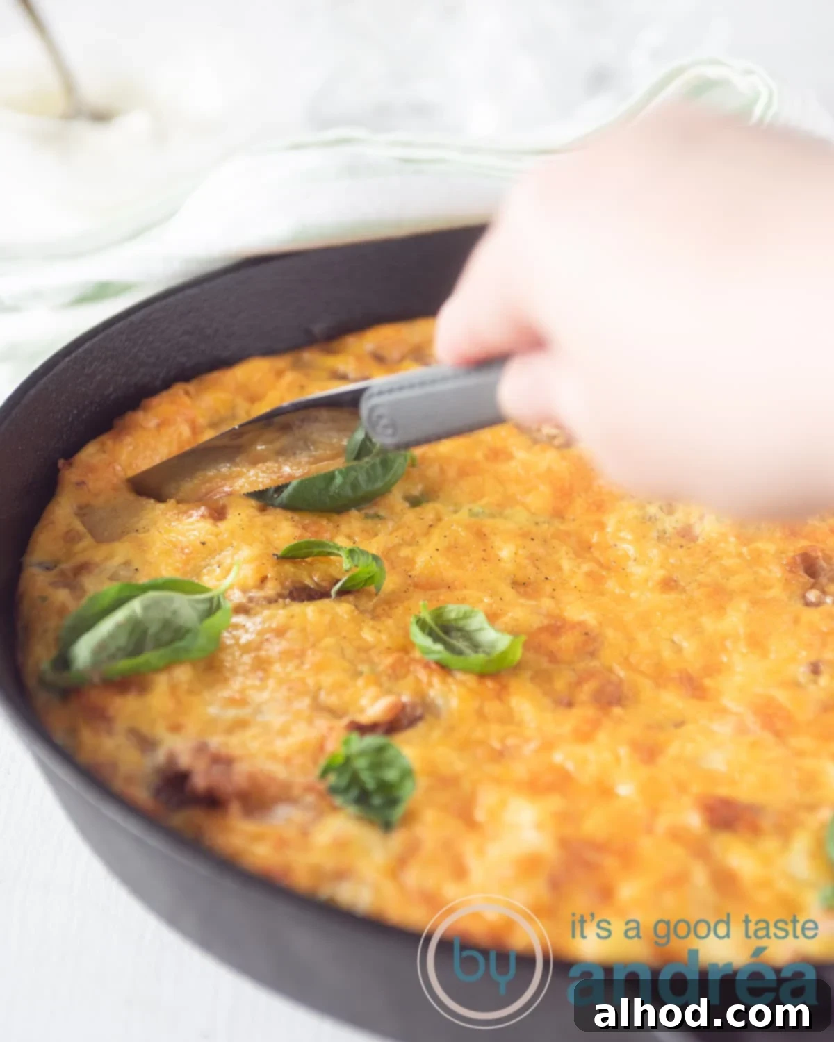 Savory Bacon and Golden Spanish Tortilla Bake 2 A fully loaded Spanish tortilla in a cast iron pan. A knife is slicing through the omelet