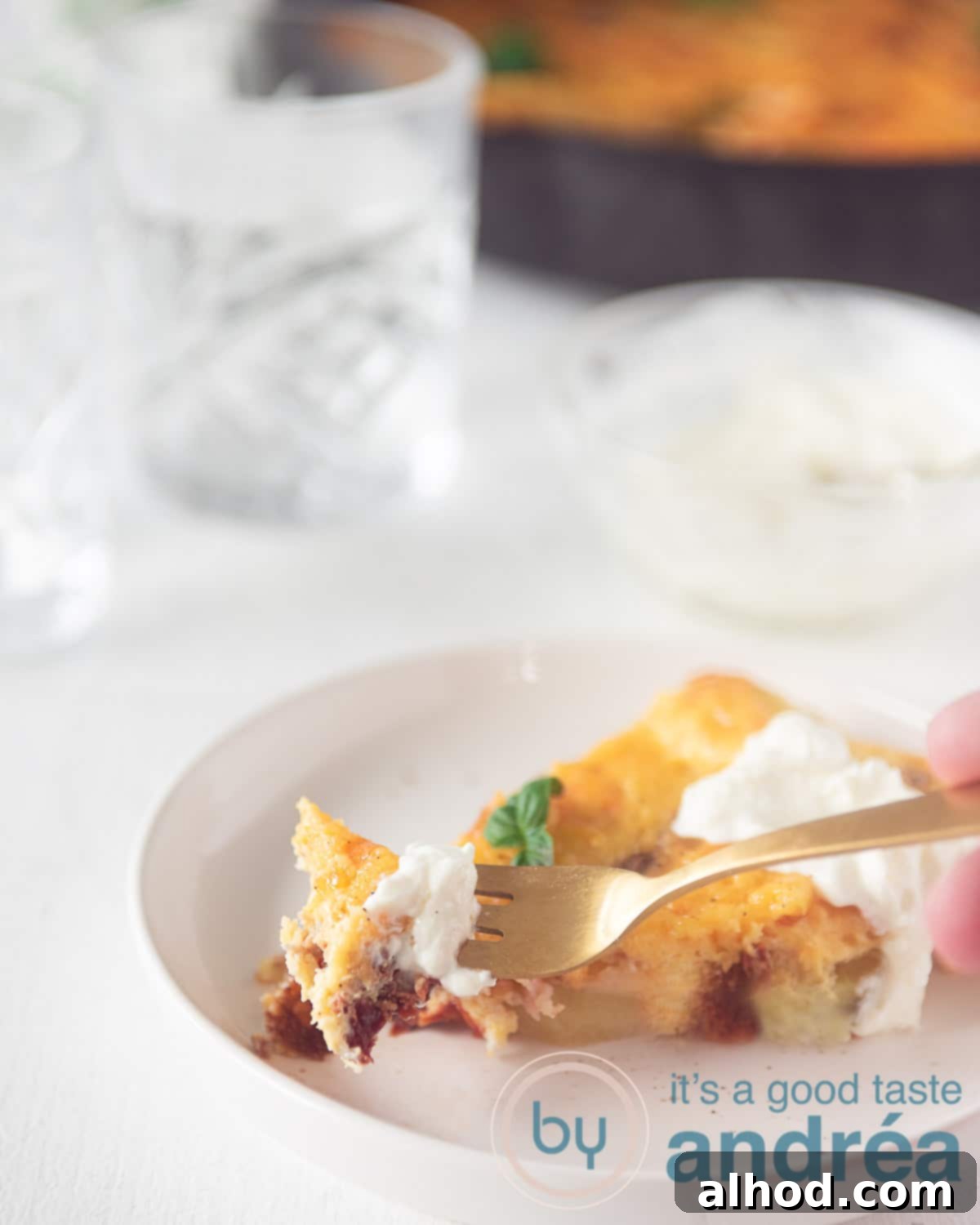 Savory Bacon and Golden Spanish Tortilla Bake 8 A slice of Spanish tortilla with a dollop of sour cream. A golden fork is taken a bite of it.