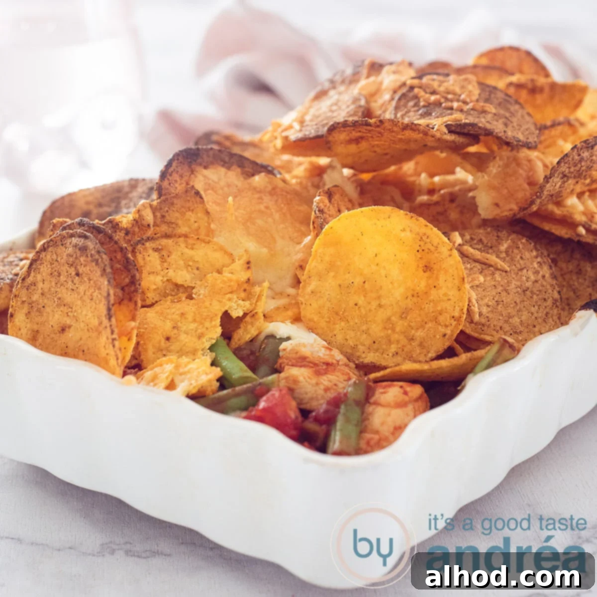 11 Amazing Mexican Recipes to Ignite Your Home Fiesta 3 A hearty square photo of a chicken casserole generously topped with crispy nachos and melted cheese, ready to be served for a festive meal.