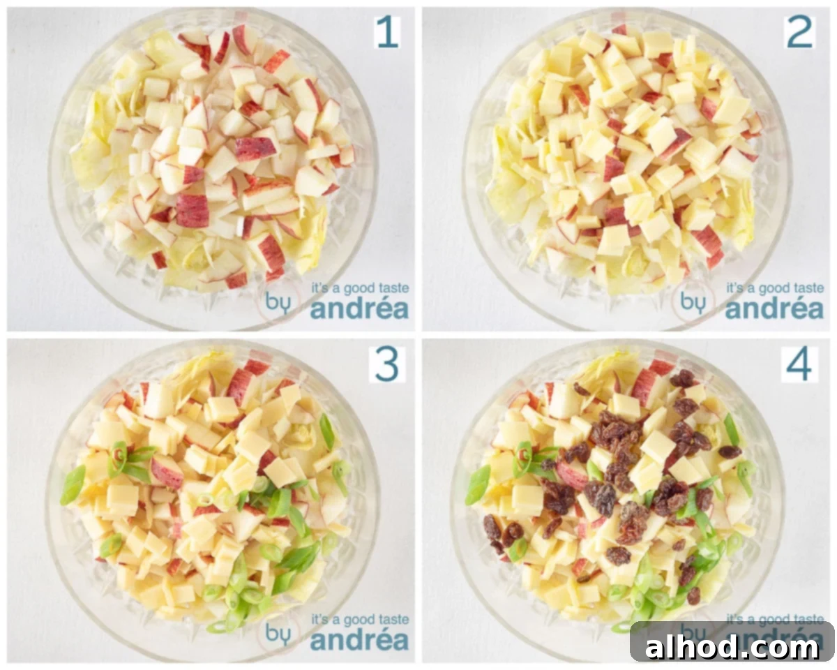 A large salad bowl filled with prepared chicory, diced apples, and cubed cheese, illustrating the assembly of the salad ingredients before the dressing is added.