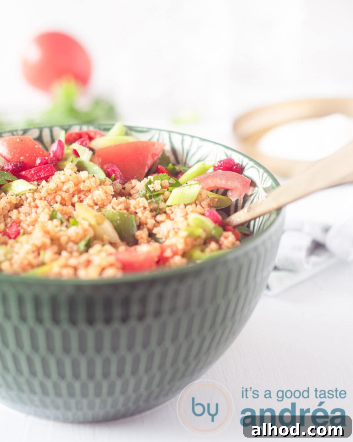 The Essential Turkish Kisir A Flavorful Bulgur Salad 2 A green bowl with vibrant Turkish Bulgur salad, garnished with pomegranate seeds and fresh tomatoes, ready to be served.