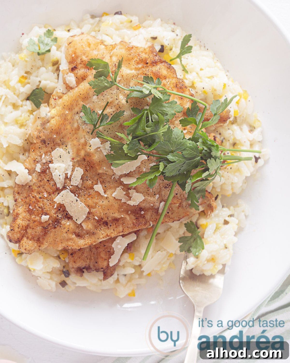 Flaky Cod and Fresh Zucchini Risotto 2 Photo from above of a white plate filled with risotto on which 2 cod fillets lie. Sprinkle parsley on top