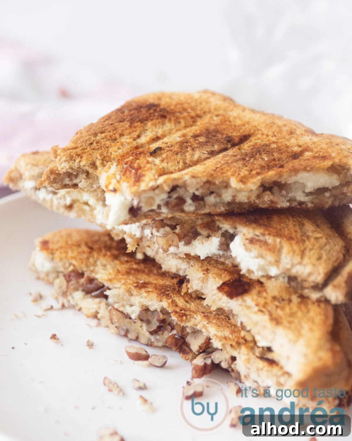 Honeyed Pecan Goat Cheese Melt 6 An elevation photo with a macro of three half slices of toasted sandwich filled with goat cheese, walnuts. In the background a white background and a pink white checkered tea towel